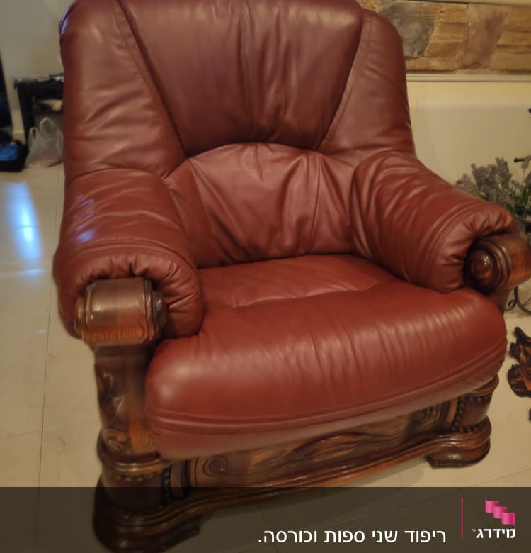 כורסה מרופדת בעור חום כהה עם מסגרת עץ מעוצבת